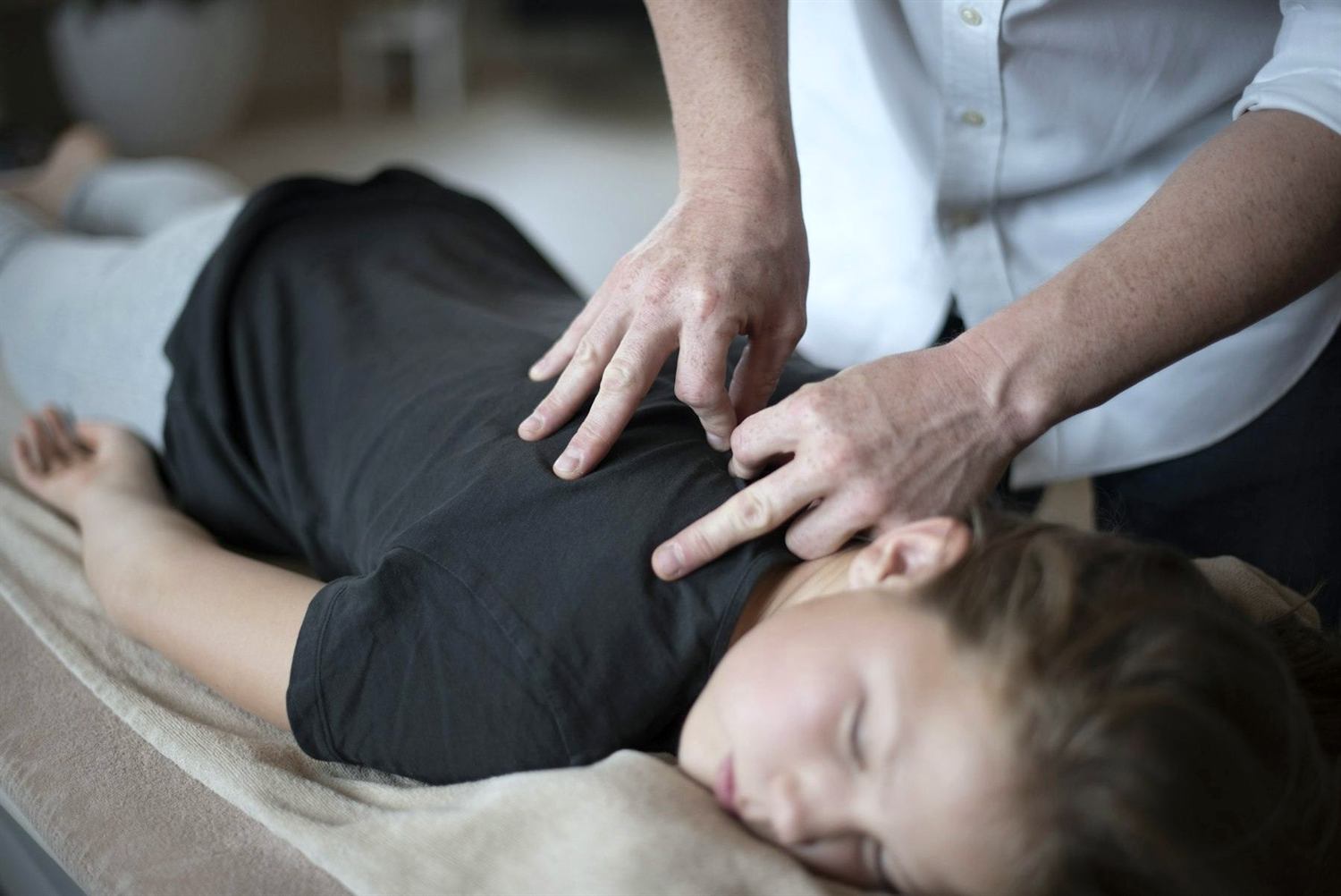Hands resting on a patient's shoulders during treatment