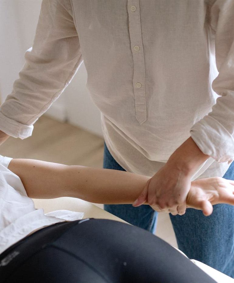 A chiropractor guiding a patient's arm through a stretch